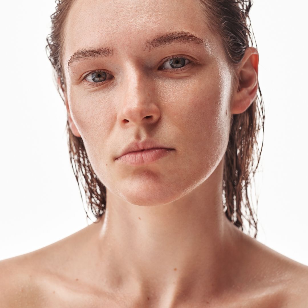 Moteris rodo drėgną, gaivią odą po sausai odai skirto rinkinio naudojimo.